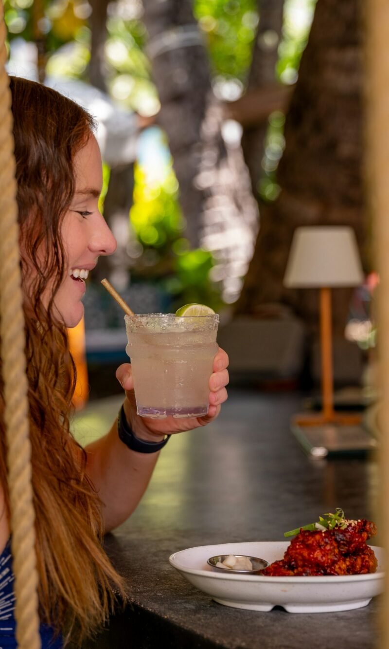 A woman enjoys a meal and a drink at an outdoor seating area.