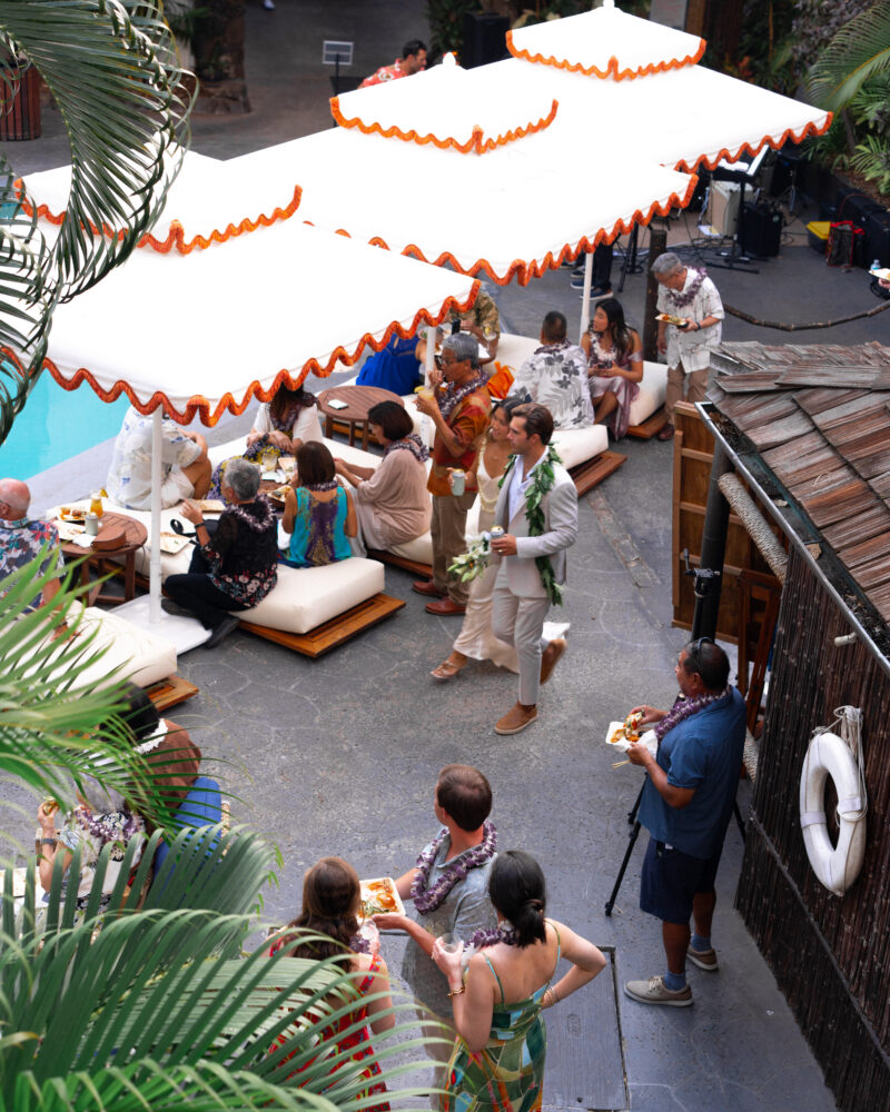 A group of people gathered around a pool with white umbrellas