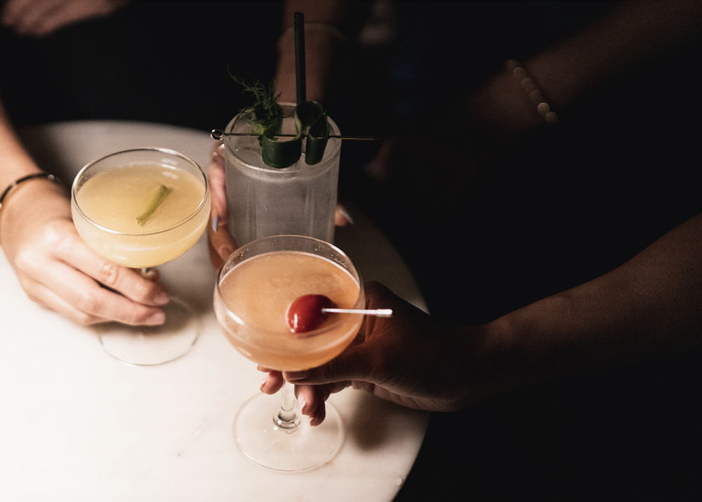 three hands holding cocktail glasses
